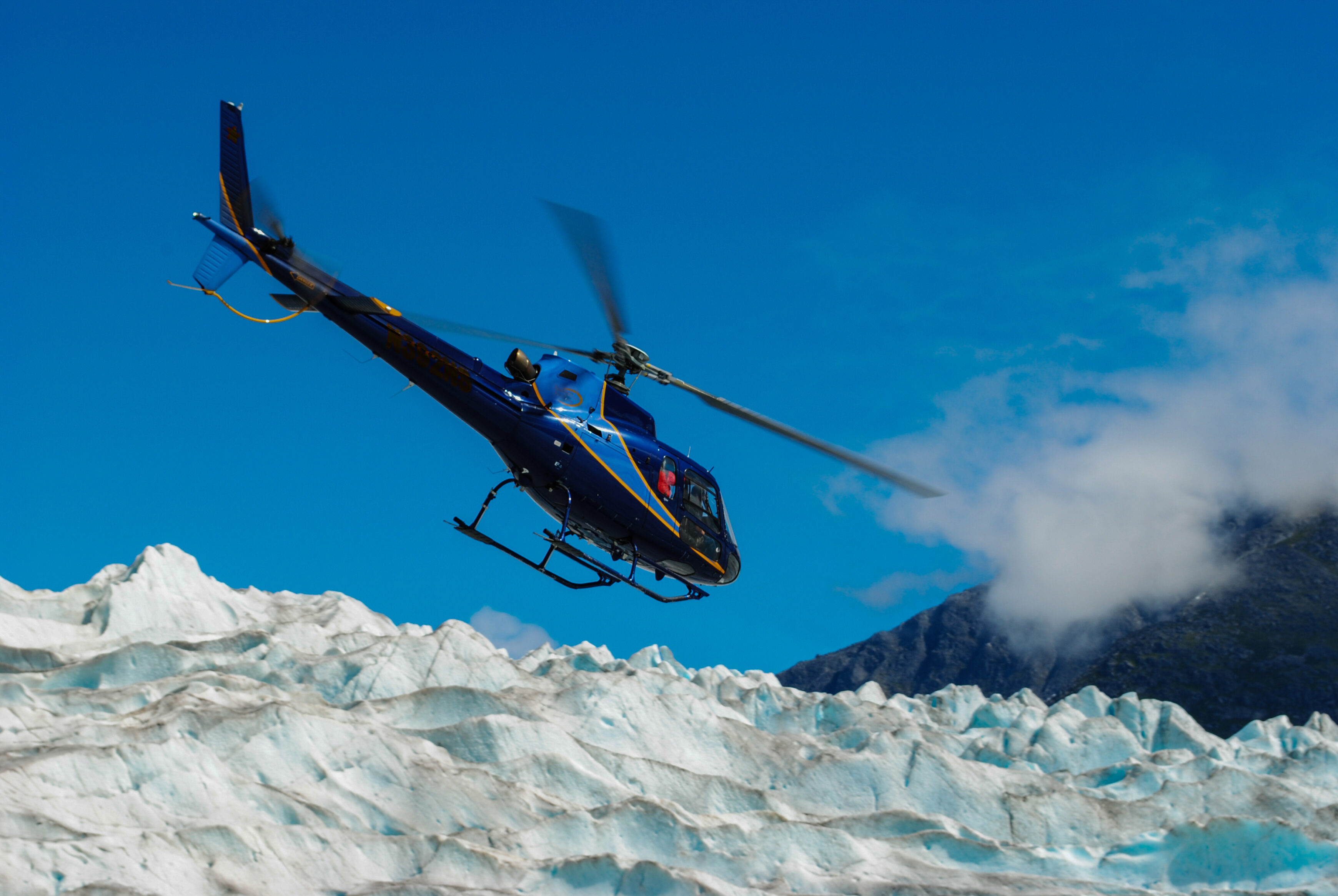 Blue Helicopter Flying Low Over an Alaskan Glacier